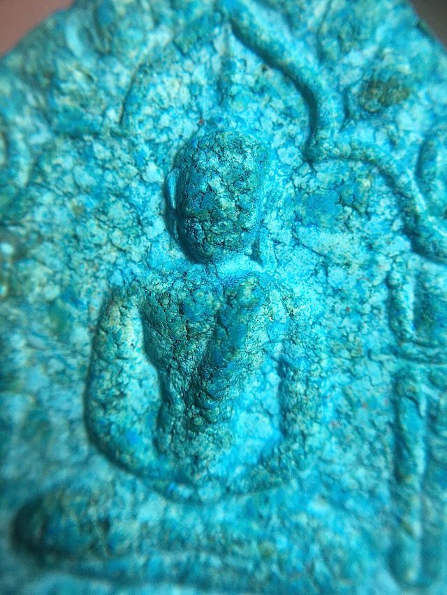 Close up macro image of the front face of the amulet showing the main central section of the Buddha image revealing the sacred muan sarn ingredients within the admixture