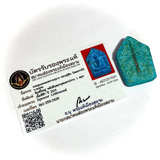 Certificate of authenticity with the amulet seen from the front face laid to the right hand side of it