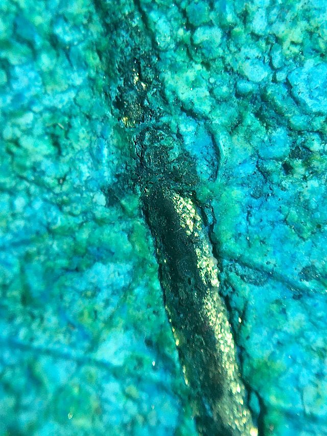 Macro cross up image of the Takrut Maha Braab inserted into rear face of the amulet showing its natural age