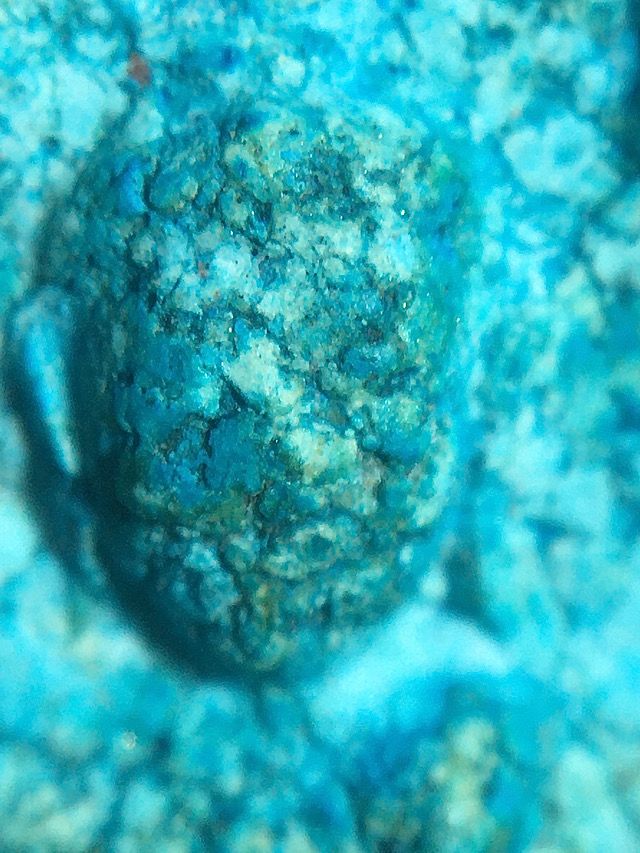 Macro close up showing the details of the sacred clay within the face of the Buddha on the front face of the amulet