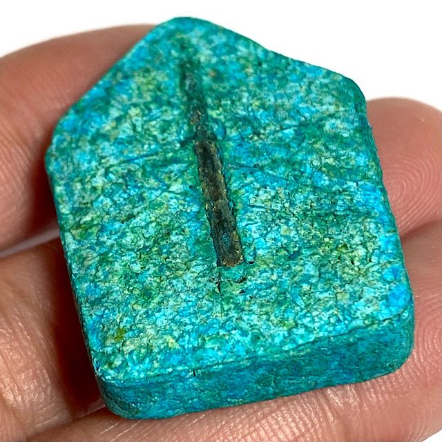 Rear face of the amulet held in the hand seen at an angle from the bottom edge